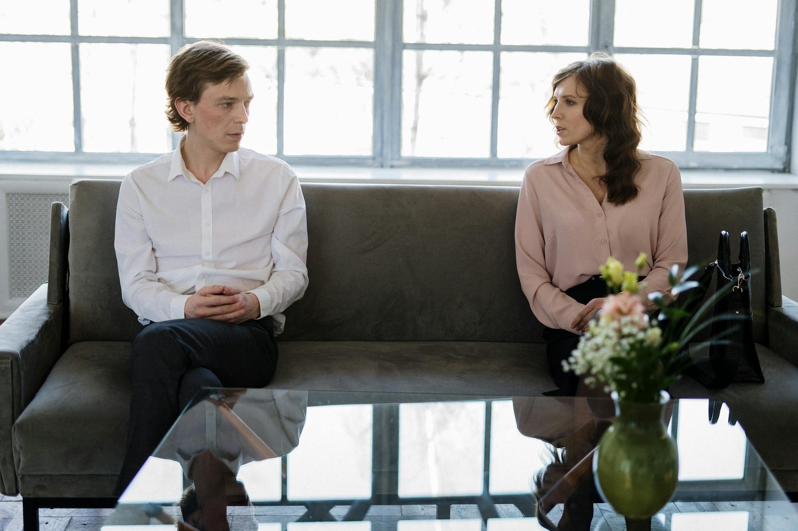 A couple engaged in a therapy session, seated on a couch in a bright modern office.